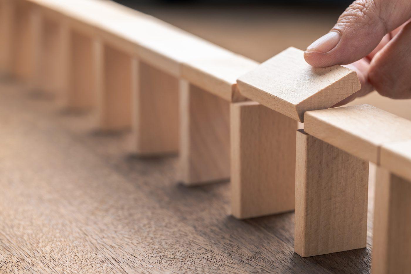 A hand placing the final wooden block to complete a standing row